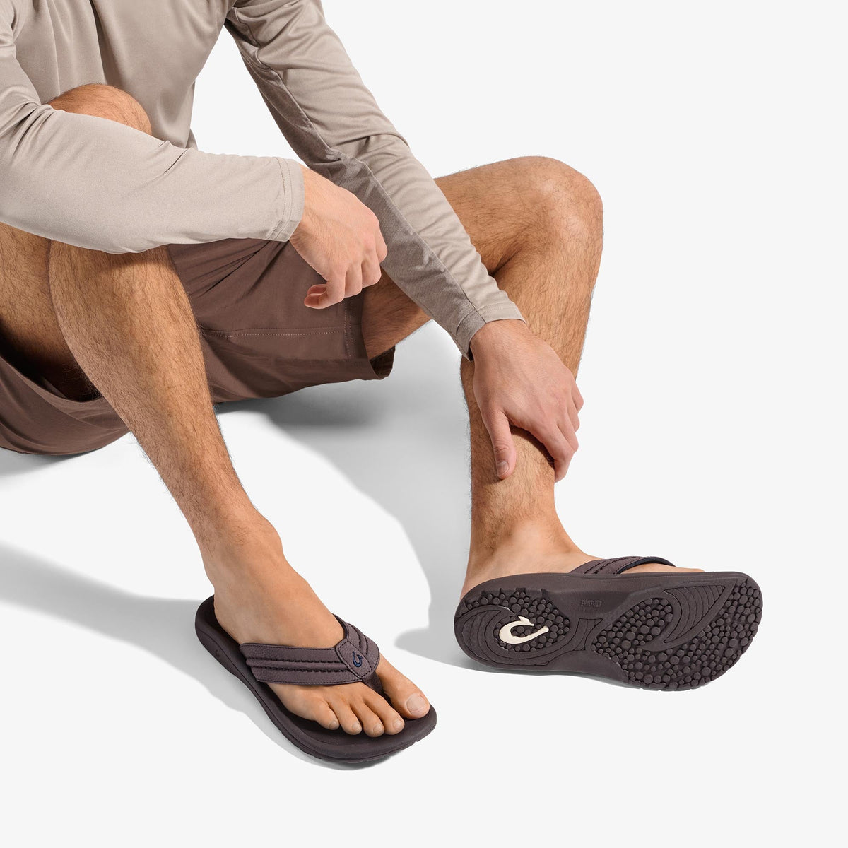 Man wearing dark brown flip-flop sandal with textured sole and adjustable strap.
