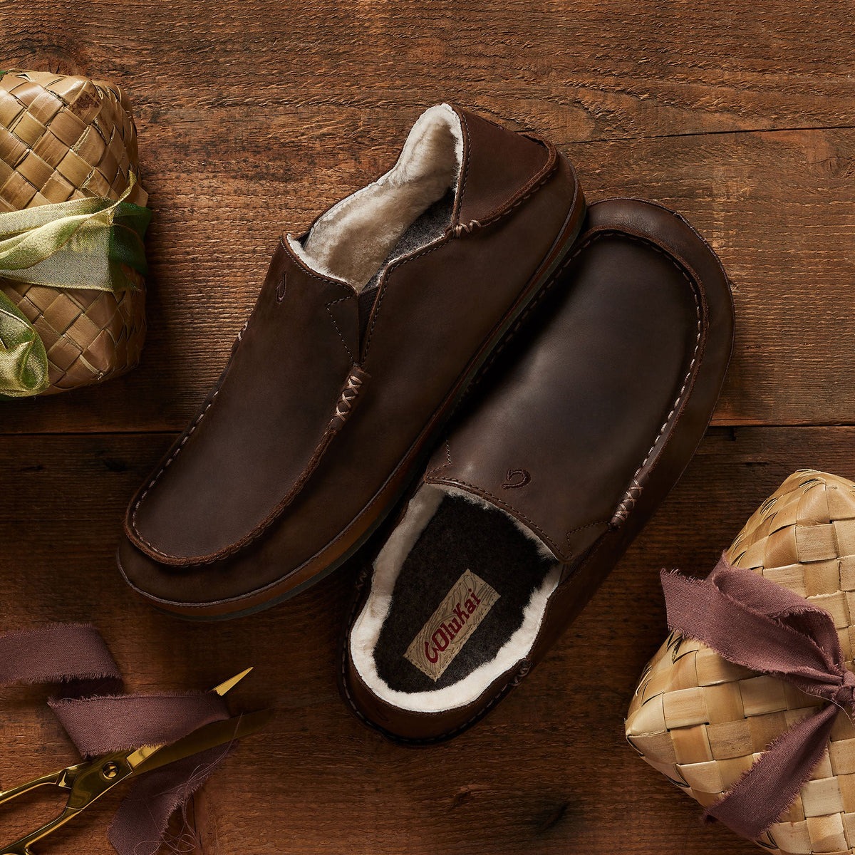 Dark brown leather slipper with fleece lining, shown from top and side view on wooden surface.
