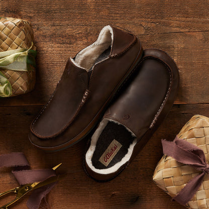 Dark brown leather slipper with fleece lining, shown from top and side view on wooden surface.