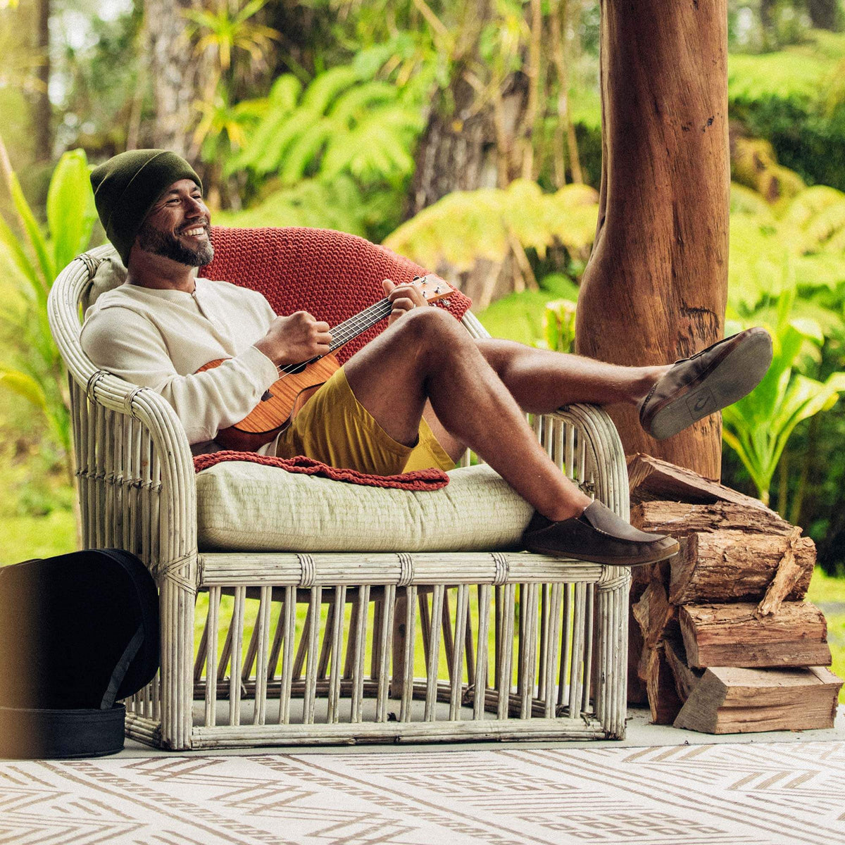 Dark wood slipper with textured sole worn by person seated outdoors.