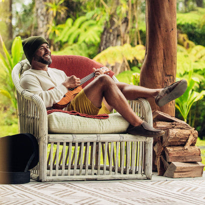 Dark wood slipper with textured sole worn by person seated outdoors.