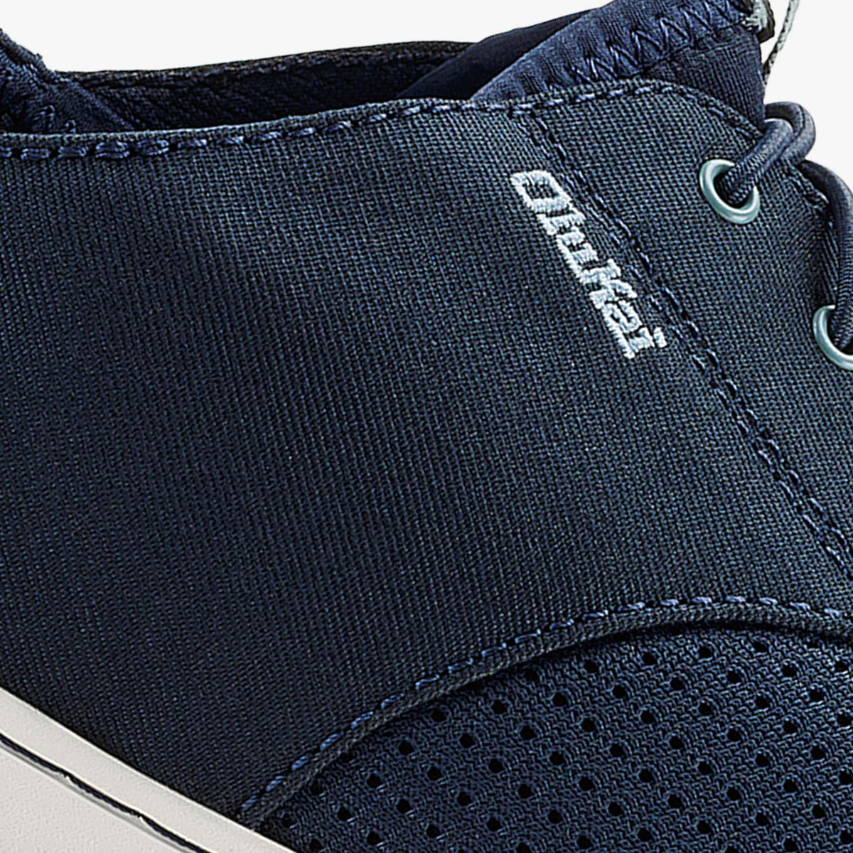 Dark blue canvas slip-on shoe with textured upper, white brand stitching, and metal eyelets.