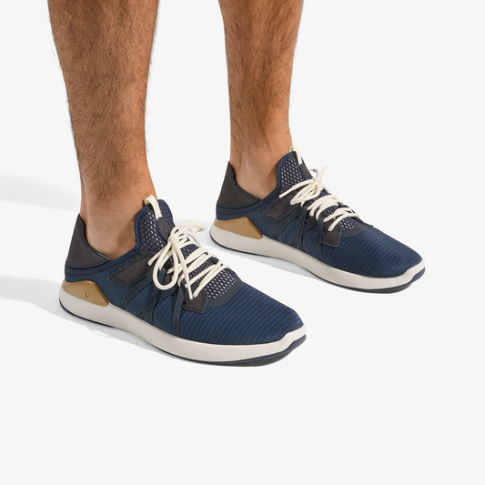 Blue and natural sneakers with white laces and cream-colored sole, worn on feet against white background.