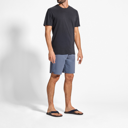 Man wearing dark navy t-shirt, blue shorts, and black slide sandals.