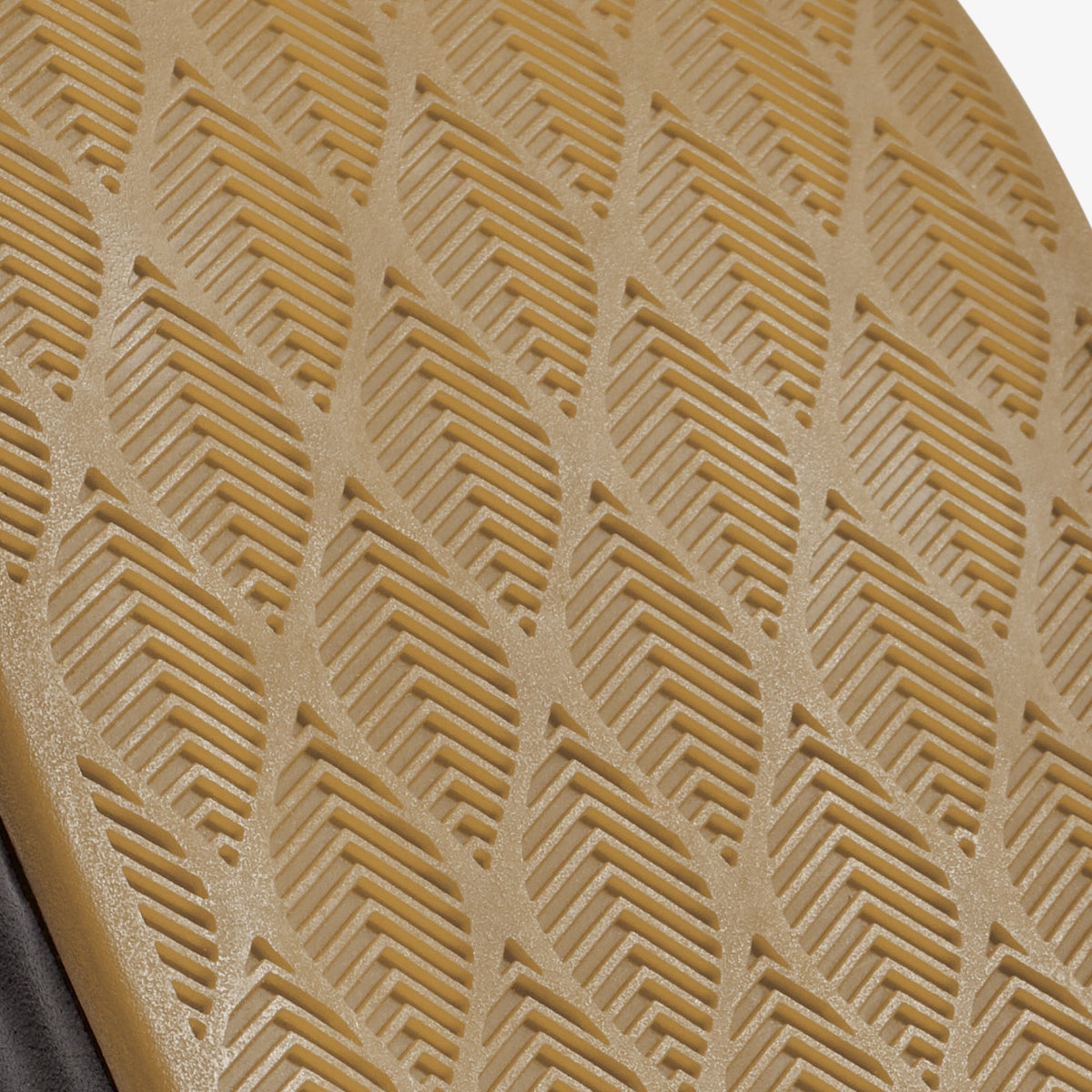 Tan fabric with geometric chevron and linear embossed pattern, edge of gray material visible at bottom.