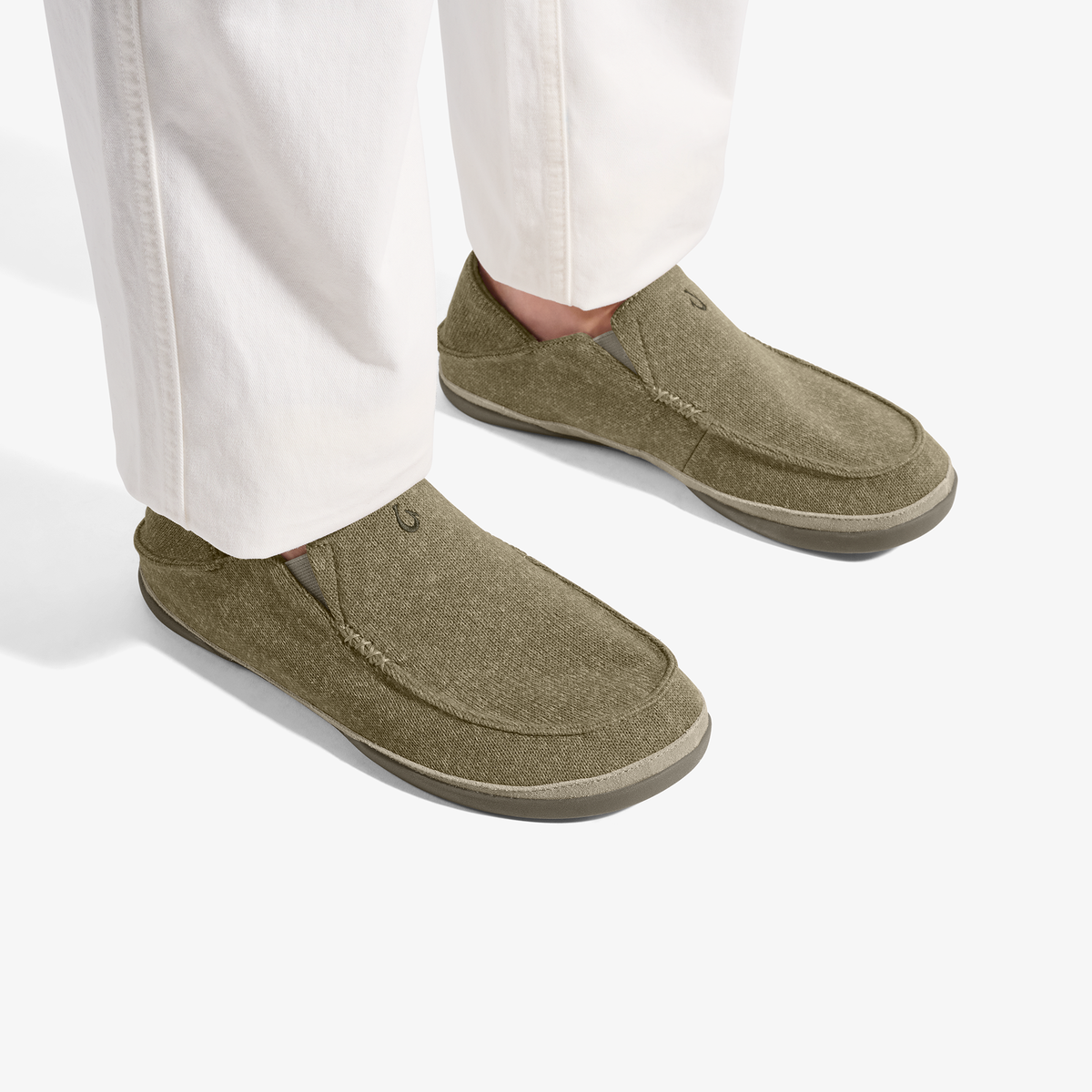 Person wearing olive green slip-on loafers with cream-colored sole and white pants.