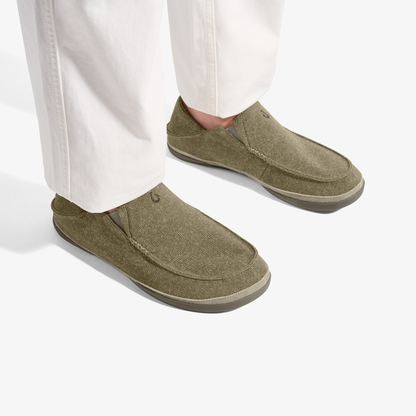 Person wearing olive green slip-on loafers with cream-colored sole and white pants.