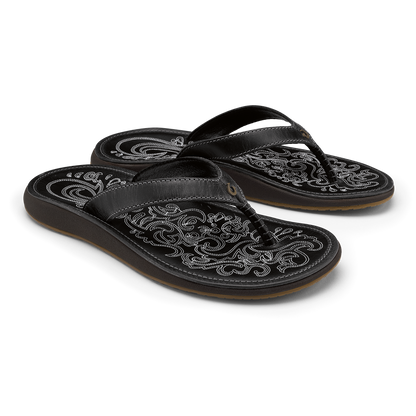 Pair of black leather flip-flops with ornate white embroidered patterns on footbeds and straps.