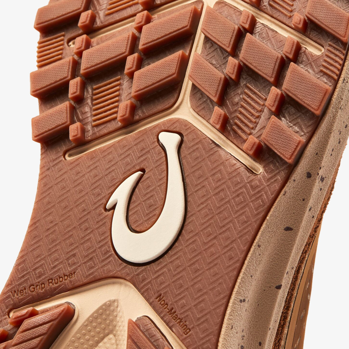 Shoe sole with cream-colored hook logo, terracotta rubber tread pattern, and geometric textured grip surface.