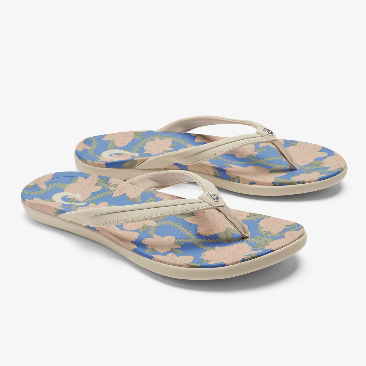 Pair of flip-flops with cream straps and footbeds featuring a marine blue base with peach and green floral pattern.