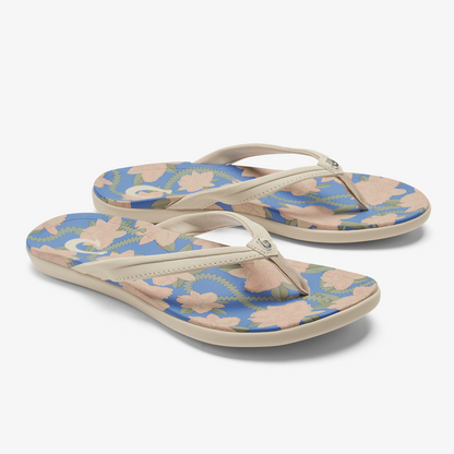 Pair of flip-flops with cream straps and footbeds featuring a marine blue base with peach and green floral pattern.