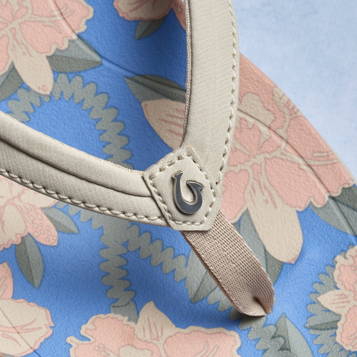 Cream handle with metal clasp detail on tapa fabric tote featuring pink, blue, and gray floral pattern.