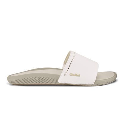 White and tan slide sandal with ribbed sole and decorative stitching on upper strap.
