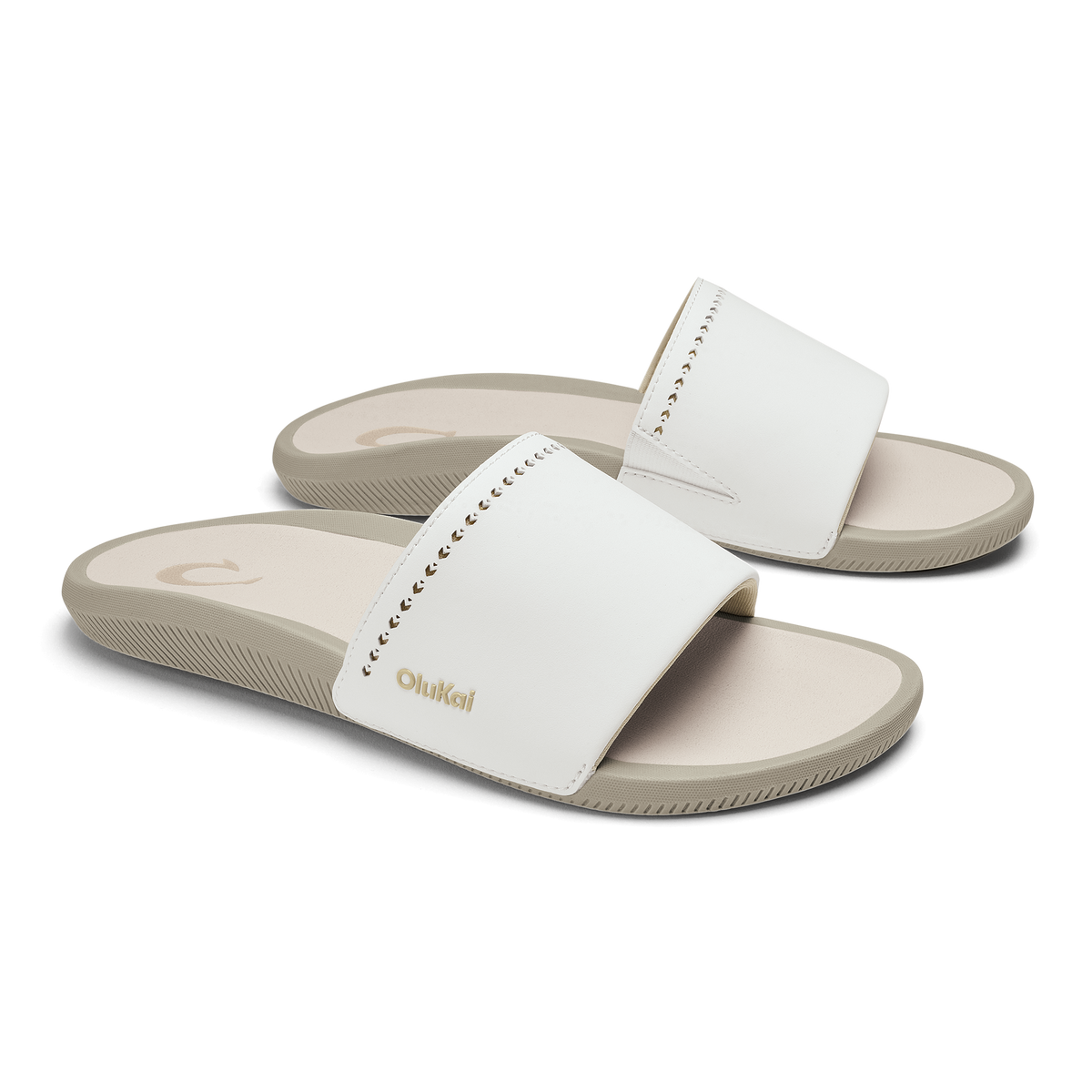 White slide sandals with textured straps and beige soles, shown in pairs from a three-quarter view.
