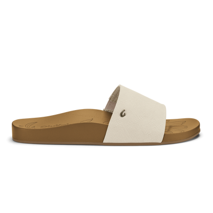 Tan slide sandal with cream textured upper strap and small metal rivet detail.