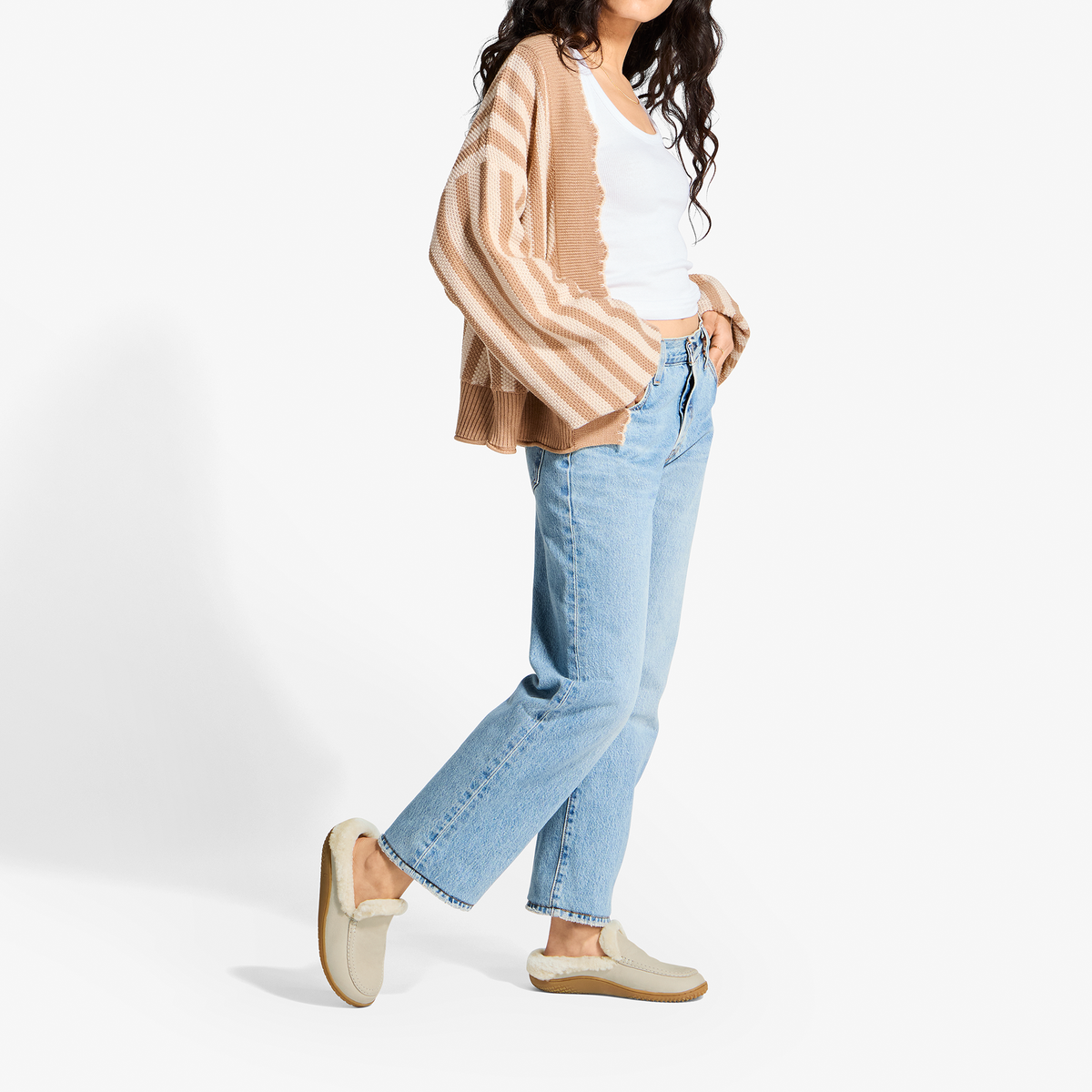 Woman wearing ecru striped cardigan, white tank top, light blue jeans, and ecru slip-on loafers.