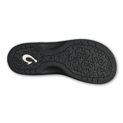 Black shoe sole with ornamental scroll pattern and silver curved logo detail.